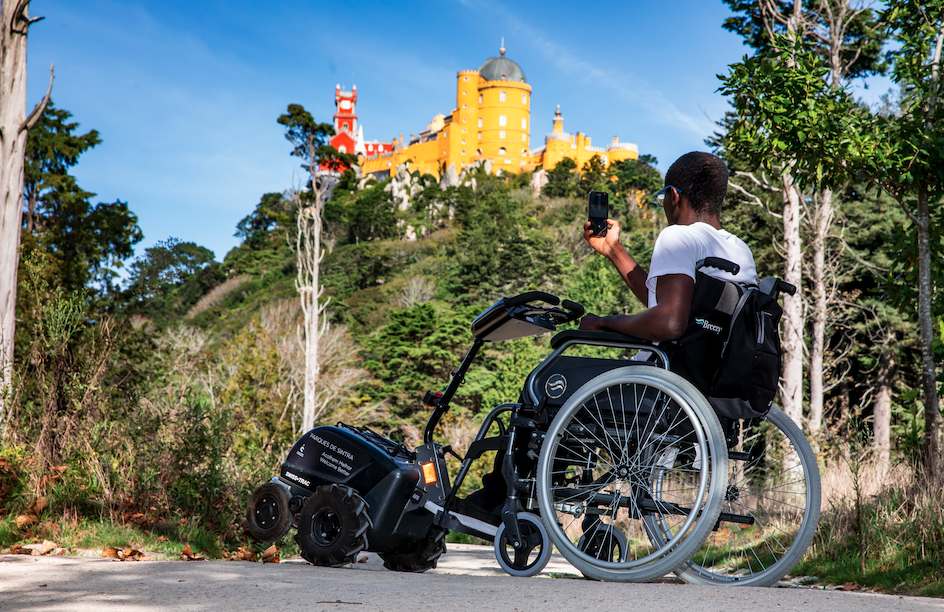 Wheelchair user taking photo of yellow castle on hilltop at Sintra 